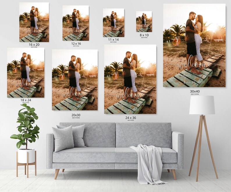 May include: A wedding welcome sign with a couple standing on a wooden dock. The sign says "Welcome" with the date "June 26, 2021" underneath. The couple is wearing white clothing and is standing in front of a sunset.