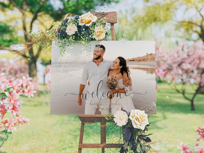 May include: A wedding welcome sign with a photo of a couple on a beach. The sign says "Welcome" with the couple's names, "Daniela & Sophia", and the date "June 26, 2021".