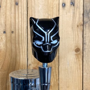 May include: Black and silver beer tap handle featuring a Black Panther head design.