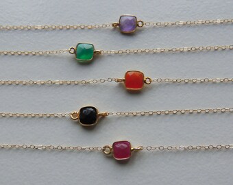 May include: Five gold chains with square-shaped gemstones in different colors. The gemstones are purple, green, orange, black, and pink.
