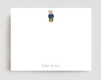 May include: White stationery card with a watercolor illustration of a teddy bear wearing a blue sweater and green pants. The text "baby henry" is printed in a soft blue color at the bottom of the card.