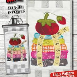 May include: A machine embroidery design featuring a stack of colorful fabric scraps with a red tomato on top. The design includes a measuring tape wrapped around the stack. The design is titled "Sew Necessary" and is available in three different stitch styles: satin, blanket, and traditional. The design is 6 inches by 12 inches and requires an 8 inch by 12 inch hoop.
