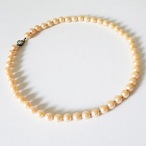 May include: A strand of cream-coloured faux pearl beads with a silver clasp.