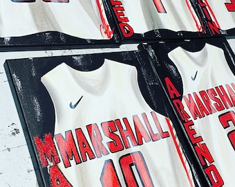 May include: Four white basketball jerseys with black outlines and red numbers. The jerseys are framed and displayed on a black background. The names "MARSHALL" and "REED" are written on the jerseys.