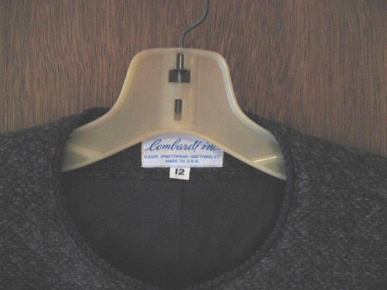 May include: A black sweater with a blue label that reads "Lombardi Inc. Classic Sportswear - Washable - Made in U.S.A." and "12" on a white hanger.
