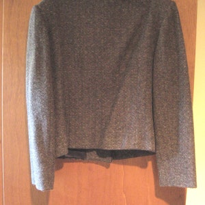 May include: A gray tweed blazer with a classic design. The blazer has a notched collar, long sleeves, and a single button closure.