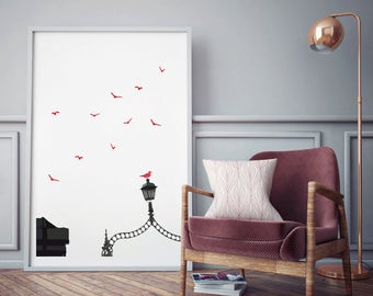 May include: A white framed print featuring a black silhouette of a street lamp with a red bird perched on top. The print has a white background with red birds flying in the sky.