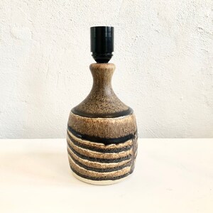 以下が含まれることがあります： 黒と茶色のセラミック製のテーブルランプで、黒いシェードが付いています。ランプにはストライプ模様があります。