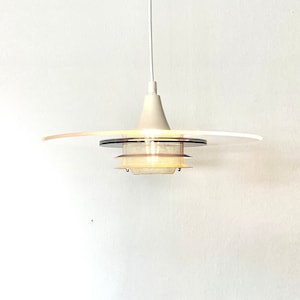 May include: A white pendant light with a circular, frosted glass shade and a metal mesh diffuser. The light is suspended from a white cord.