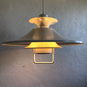 May include: A white ceiling light fixture with a saucer-shaped shade and a smaller, round, frosted glass shade. The light is turned on and illuminating the room.