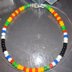 May include: A colorful beaded bracelet with black, white, blue, green, red, and yellow beads. The bracelet is made of small, round beads and has a silver clasp.