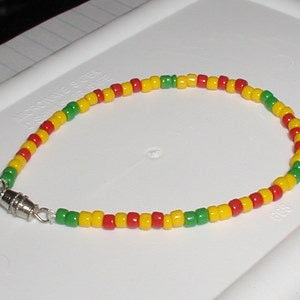 May include: A red, yellow, and green beaded ankle bracelet with a silver clasp.