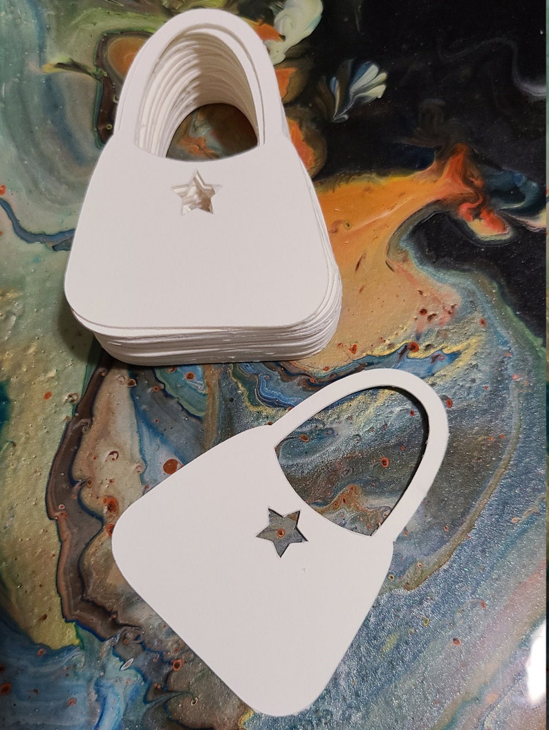 May include: A stack of white paper handbag cutouts with a star shape cut out in the center of each. The cutouts are on a colorful background.