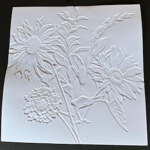 May include: A white paper relief sculpture of a bouquet of flowers. The flowers are a sunflower, a carnation, and a gladiolus. The sculpture is detailed and intricate.