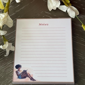 May include: A notepad with lined pages and the word "Notes" in a reddish-brown font. A watercolor illustration of a person reading a book is in the lower left corner. The notepad has a light brown border.