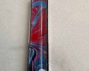 May include: A silver chain necklace with a rectangular pendant featuring abstract swirls of red, blue, black, and white paint.