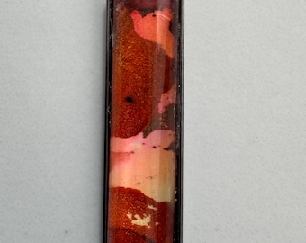 May include: A silver chain necklace with a rectangular pendant. The pendant is filled with red, orange, and pink resin with a swirling pattern.