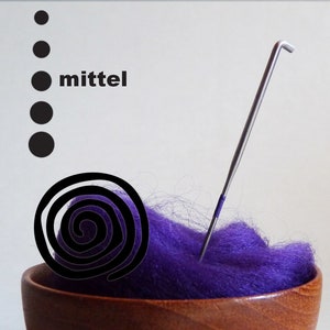 Könnte beinhalten: Ein violetter Wollrohling in einer Holzschale mit einer Metallnadel und einem schwarzen Spiralmuster. Das Wort "mittel" ist in schwarzer Schrift auf weißem Hintergrund geschrieben.