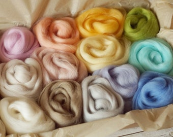 May include: A collection of ten colourful wool rovings in a variety of pastel shades, including pink, lavender, yellow, green, blue, and white. The rovings are arranged in a box, ready for use in crafting projects.