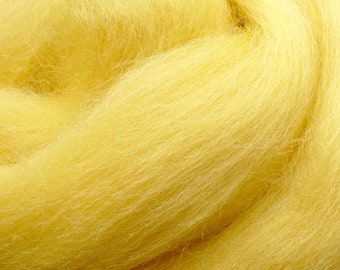 May include: A close-up shot of a mass of bright yellow wool roving. The fibres appear soft and fluffy, with a slightly textured look. The wool is a solid, sunny yellow colour, suitable for various craft projects.