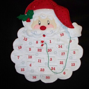 May include: White felt Santa Claus advent calendar with red numbers 1 through 25. The calendar is decorated with white snowflakes and a green holly sprig.