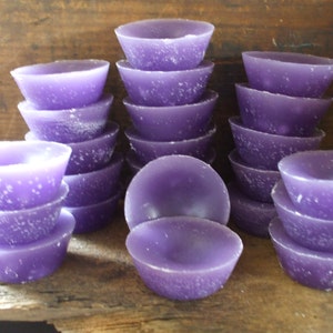 May include: A group of 15 purple wax melts in the shape of small bowls. The wax melts are stacked in groups of three and four.