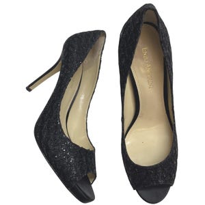 May include: A pair of black glitter peep-toe high heels. The heels have a stiletto design and a satin sole. The brand name "Enzo Angiolini" is visible on the inner sole of one shoe. The shoes are designed for formal occasions.