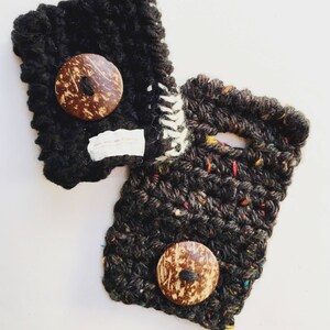 Puede incluir: Dos fundas de teléfono de punto negro con botones de cáscara de coco. Una funda tiene un patrón moteado blanco y negro.