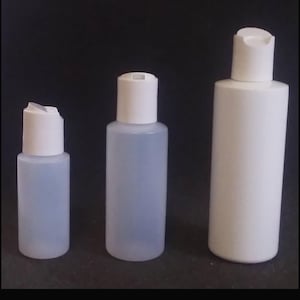 May include: Three plastic bottles with white flip-top caps. Two are translucent, and one is opaque white. The bottles vary in size, with the tallest being approximately 6 inches tall. The bottles are empty and ready for filling.