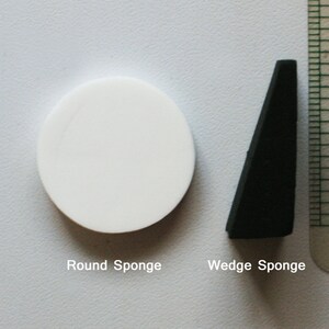 May include: Two sponges, one round and white, the other wedge-shaped and black. The text "Round Sponge" and "Wedge Sponge" is below each sponge.