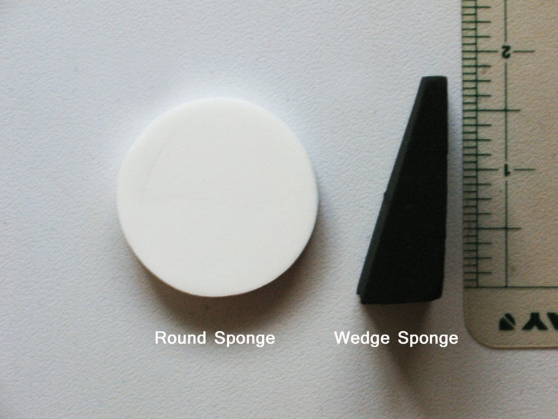 May include: Two sponges, one round and white, the other wedge-shaped and black. The text "Round Sponge" and "Wedge Sponge" is below each sponge.