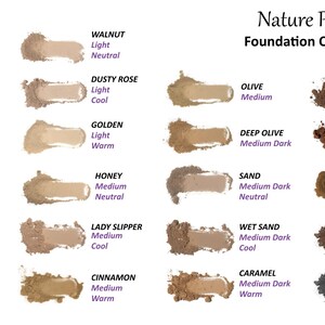 May include: Nature Provides Foundation Color Chart displaying twenty-four powder swatches in various skin tones ranging from pale to very dark. Each swatch is labeled with a name, shade intensity, and undertone, including Calla Lily, Walnut, Lotus, Dusty Rose, Cream, Golden, Birch, Honey, Olive, Deep Olive, Vanilla, Cacao, Cherry Blossom, Lady Slipper, Sand, Burnt Sugar, Cashew, Cinnamon, Caramel, and Licorice.