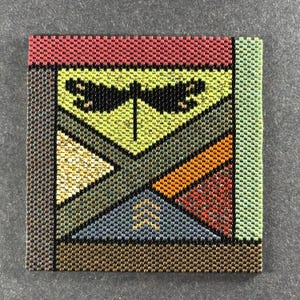 May include: Square beaded artwork featuring a dragonfly design. The artwork uses a variety of colors, including red, green, yellow, orange, and blue. The dragonfly is black. The piece is made of small, colorful beads.