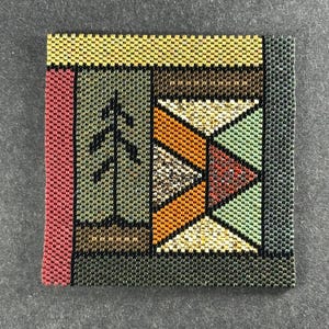May include: Square beaded artwork with a geometric design. The piece features a tree-like shape and a zig-zag pattern in shades of green, orange, red, and yellow. The border is dark grey, and the background is a neutral grey.