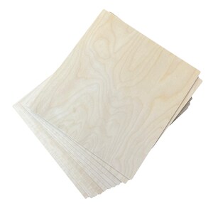 Puede incluir: Una pila de hojas de madera sin terminar de color claro. La veta de la madera es visible, con patrones arremolinados en tonos beige y marr&oacute;n. Las hojas son rectangulares y parecen estar listas para manualidades u otros proyectos.