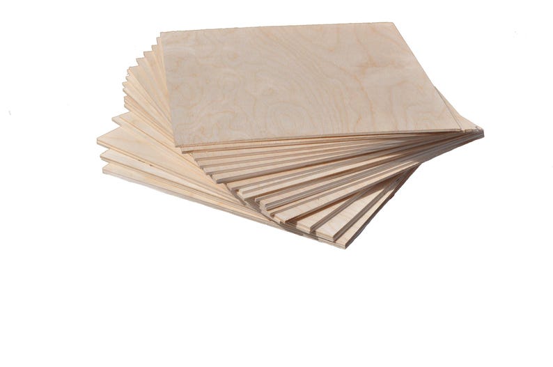 Puede incluir: Una pila de tablas de madera sin terminar de color claro. Las tablas son rectangulares y parecen ser de madera contrachapada. La veta de la madera es visible y las tablas est&aacute;n apiladas en forma de abanico.