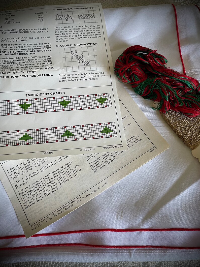 K&ouml;nnte beinhalten: Kreuzstich-Stickset mit Anleitungen und Diagrammen. Enth&auml;lt ein Blatt mit einem Weihnachtsbaum-Muster, rotes und gr&uuml;nes Stickgarn und wei&szlig;en Stoff mit rotem Rand. Das Set ist zum Basteln.