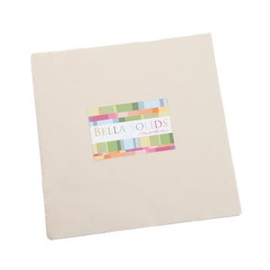 May include: A square, off-white fabric piece with a colorful rectangular label that reads "BELLA SOLIDS moda". The label features a pattern of horizontal stripes in various colors. The fabric appears to be a quilting cotton.