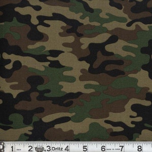 May include: Camouflage fabric with a pattern of irregular shapes in shades of green, brown, and black. A measuring tape is along the bottom, showing inches.