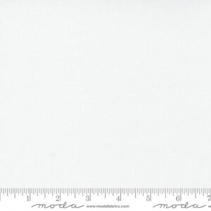 May include: A close-up of a white fabric with a subtle woven texture. The fabric is plain and evenly lit, with a ruler along the bottom edge. The fabric is suitable for quilting, sewing, and various craft projects.