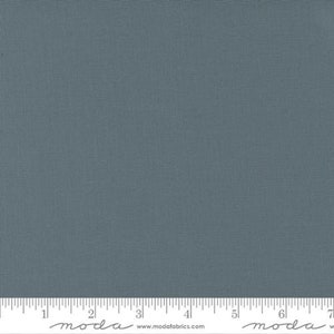 May include: A solid blue fabric swatch with a subtle texture. The fabric is displayed on a ruler with markings in inches.
