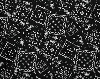 May include: A black fabric featuring a repeating white bandana print with square borders, floral motifs, and paisley shapes. A white measuring tape is positioned at the bottom, showing a length of 8 inches with the brand name Dritz clearly visible.