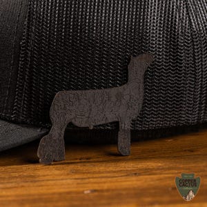 May include: A black trucker cap featuring a dark brown dog silhouette with a floral pattern. The cap sits on a wooden surface. The Copper Cactus logo is visible in the bottom right corner. The hat has a mesh back.