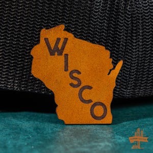 May include: A brown leather patch shaped like the state of Wisconsin with the word "WISCO" written vertically down the center.