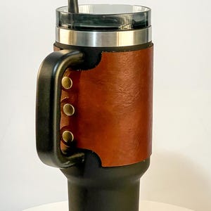 May include: A black tumbler with a brown leather wrap and a black handle. The tumbler has a silver rim and a clear lid with a black straw. The words "DIGITAL DOWNLOAD" are printed on the bottom left.