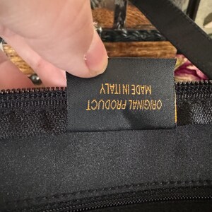 May include: Close-up of a black zipper with a gold tag that reads "ORIGINAL PRODUCT MADE IN ITALY".