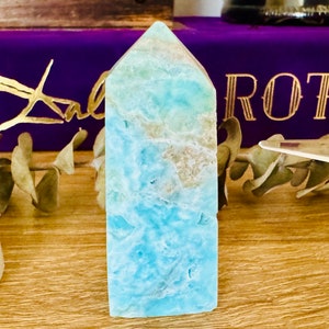 May include: A light blue aquamarine crystal point with white veining. The crystal is polished and has a smooth, glassy surface.