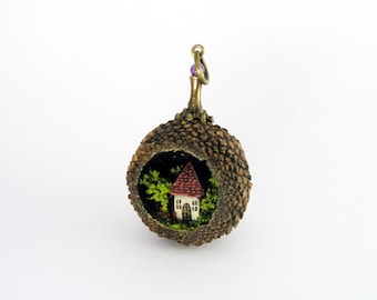 Miniature world pendant. Tiny house amidst trees and flowering bushes in real acorn.