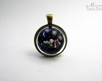 Miniature World pendant. A romantic fantasy scene of a man and woman are sitting on a cloud travelling through the starry night.