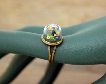 Miniature flower garden in a a glass dome. Adjustable brass ring.